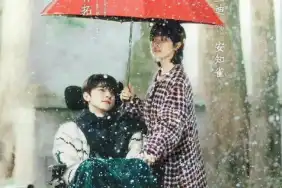 Lin Yi sits on a wheelchair while Landy Li holds an umbrella over his head