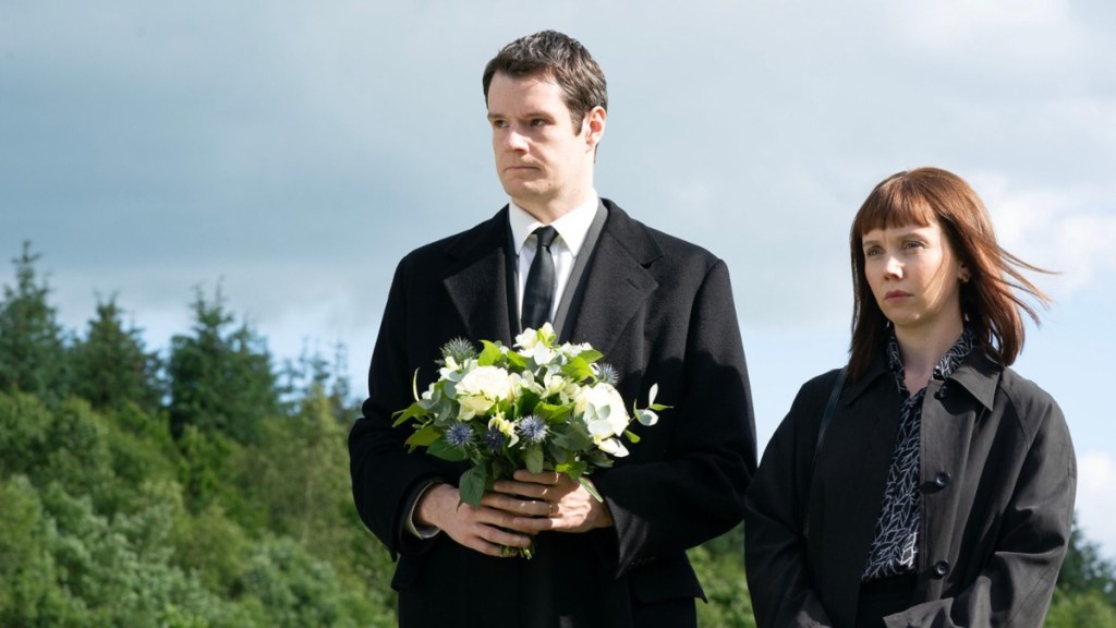 A man holds flowers next to a woman.