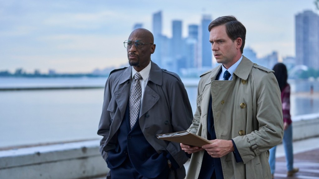 Two men stand outside the water.