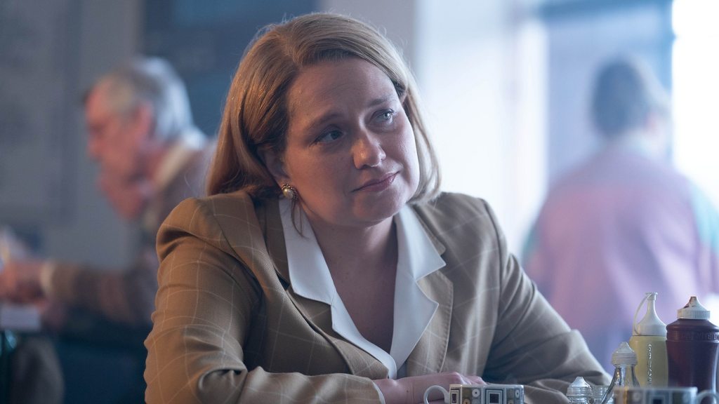 A woman sits at a table and stares.