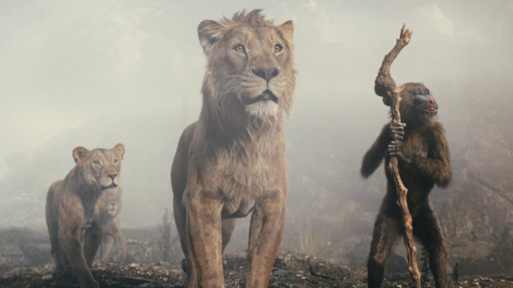 Two lions stand next to a mandrill.