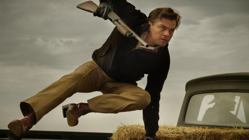 Leonardo DiCaprio hops over a car.