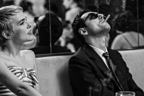 A woman sits next to a man smoking.