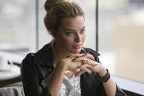A woman sits with her hands under her chin.