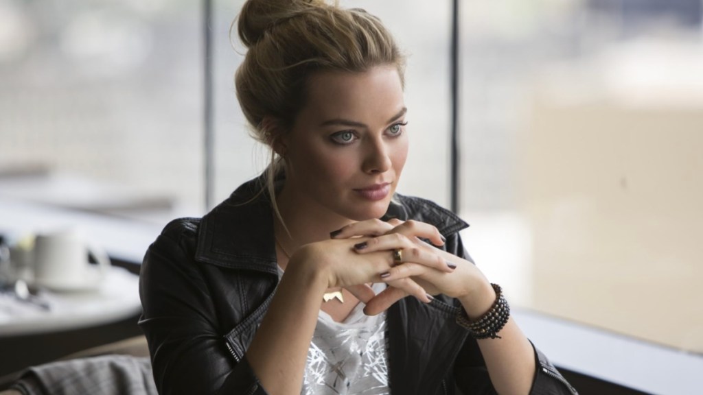 A woman sits with her hands under her chin.
