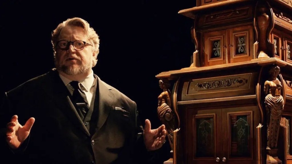 Guillermo del Toro stands in front of a clock.