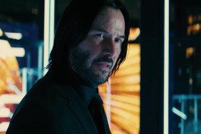 Keanu Reeves stares through the window as John Wick.