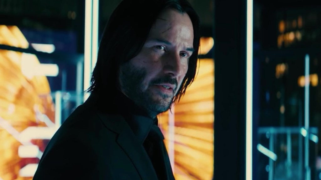Keanu Reeves stares through the window as John Wick.