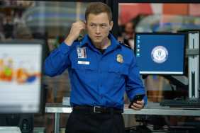 Taron Egerton puts an ear piece on in Carry-On.