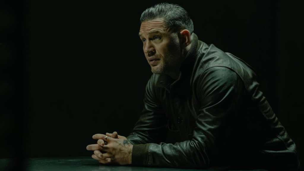 Tom Hardy sits at a table in MobLand.